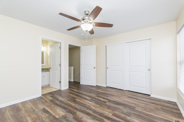 unfurnished bedroom featuring a closet, baseboards, dark wood-style floors, and ensuite bath