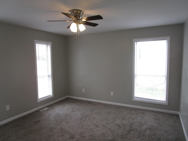 spare room with carpet floors, ceiling fan, visible vents, and plenty of natural light