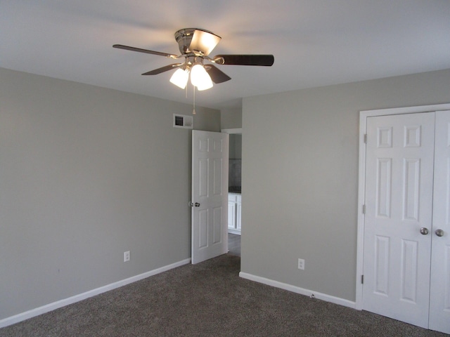 unfurnished bedroom featuring a closet, baseboards, dark colored carpet, ceiling fan, and visible vents