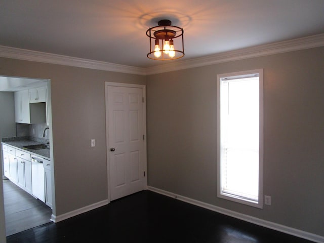 unfurnished dining area featuring a sink, crown molding, baseboards, and dark wood finished floors
