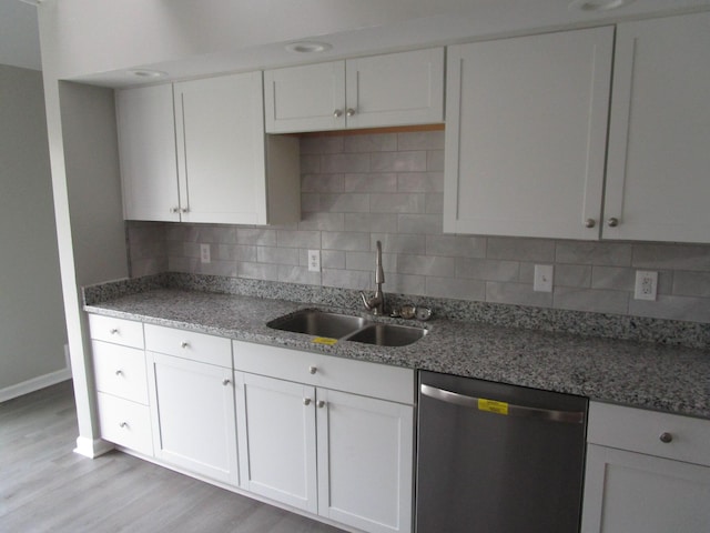 kitchen featuring light wood finished floors, a sink, stainless steel dishwasher, baseboards, and decorative backsplash