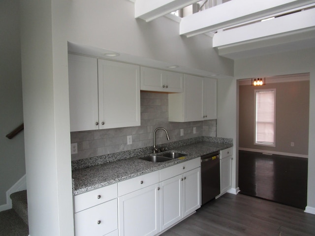 kitchen featuring a sink, white cabinetry, decorative backsplash, stainless steel dishwasher, and baseboards