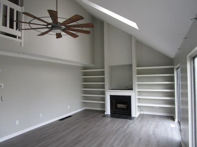 unfurnished living room featuring a fireplace with flush hearth, visible vents, high vaulted ceiling, and a skylight