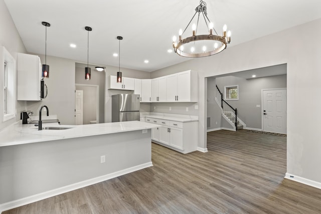 kitchen with a peninsula, appliances with stainless steel finishes, wood finished floors, and a sink