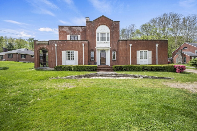 view of front of property featuring a chimney, brick siding, and a front yard