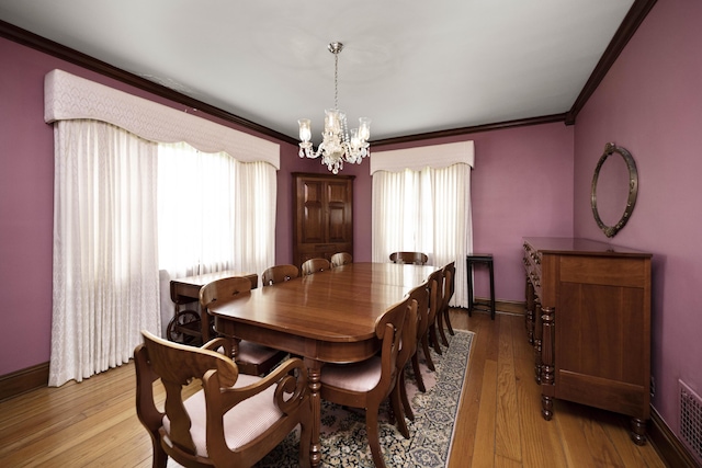 dining space featuring an inviting chandelier, wood finished floors, visible vents, crown molding, and baseboards