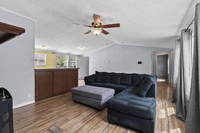 living room with vaulted ceiling, a ceiling fan, wood finished floors, a textured ceiling, and visible vents