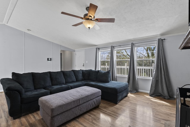 living area with baseboards, vaulted ceiling, wood finished floors, and ceiling fan