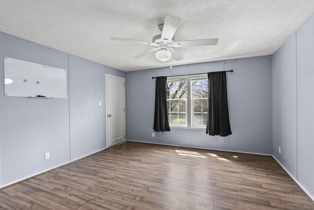 spare room with baseboards, a ceiling fan, wood finished floors, and a textured ceiling