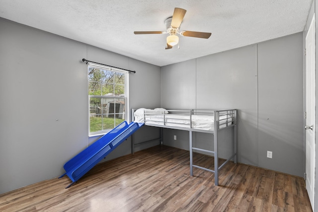 bedroom featuring wood finished floors, a textured ceiling, and ceiling fan