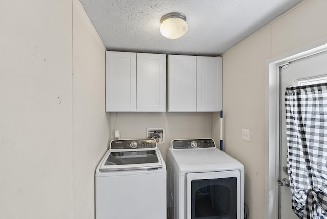 laundry room with washing machine and dryer, a textured ceiling, and cabinet space