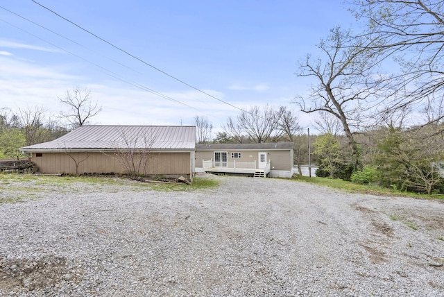 view of front of property with a wooden deck, gravel driveway, and metal roof