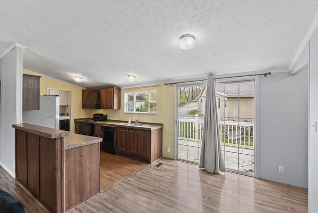 kitchen with wood finished floors, a textured ceiling, custom range hood, and black appliances