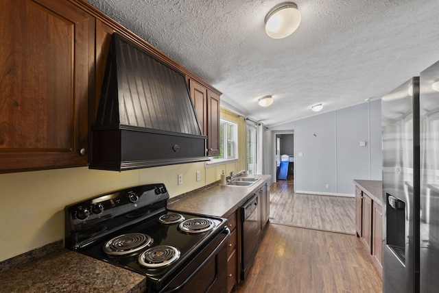 kitchen featuring dark countertops, vaulted ceiling, black appliances, a textured ceiling, and custom exhaust hood