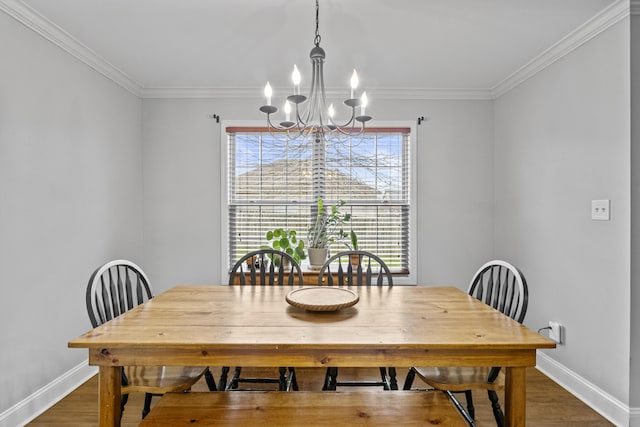 dining room with a chandelier, wood finished floors, baseboards, and crown molding