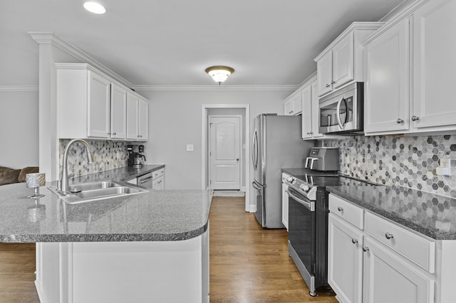 kitchen featuring stainless steel appliances, a sink, a peninsula, crown molding, and white cabinets