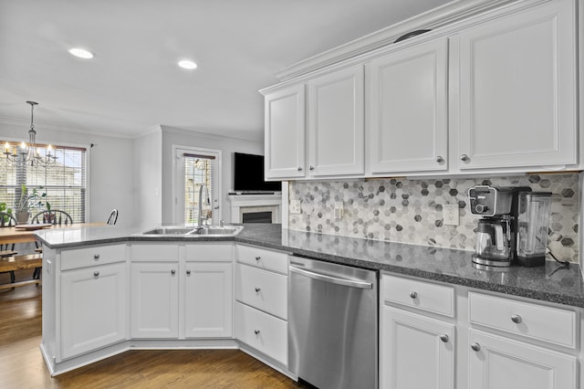 kitchen with dishwasher, a sink, a peninsula, a chandelier, and white cabinetry
