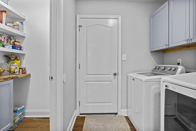 laundry room with washing machine and clothes dryer, dark wood-type flooring, cabinet space, and baseboards