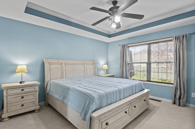 bedroom with light colored carpet, baseboards, ornamental molding, ceiling fan, and a tray ceiling