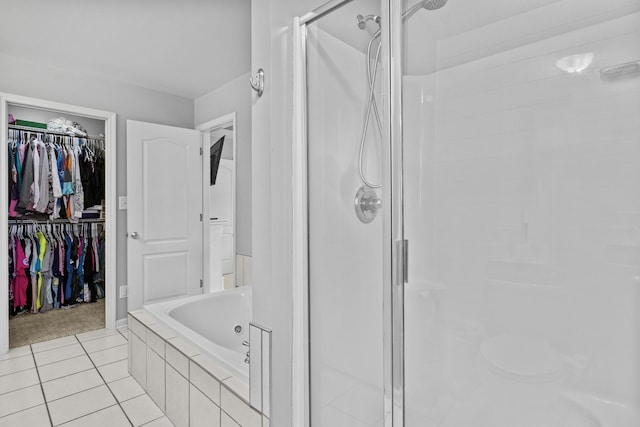 bathroom with a shower stall, a tub with jets, tile patterned flooring, and a walk in closet