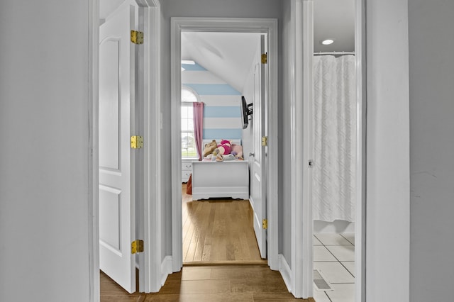 hall with vaulted ceiling and wood finished floors