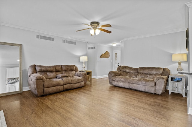 living room with ceiling fan, wood finished floors, ornamental molding, and baseboards