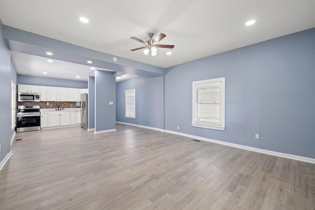 unfurnished living room featuring recessed lighting, light wood-type flooring, a ceiling fan, and baseboards