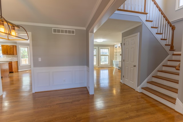 interior space featuring stairway, crown molding, visible vents, and light wood-style floors