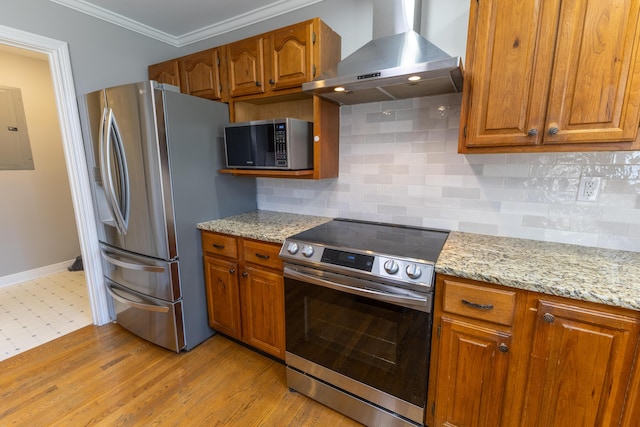 kitchen featuring brown cabinetry, wall chimney range hood, electric panel, and stainless steel appliances