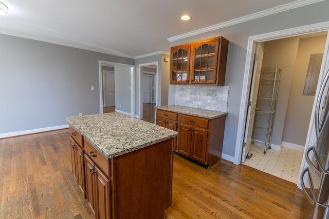 kitchen featuring brown cabinetry, tasteful backsplash, crown molding, and glass insert cabinets