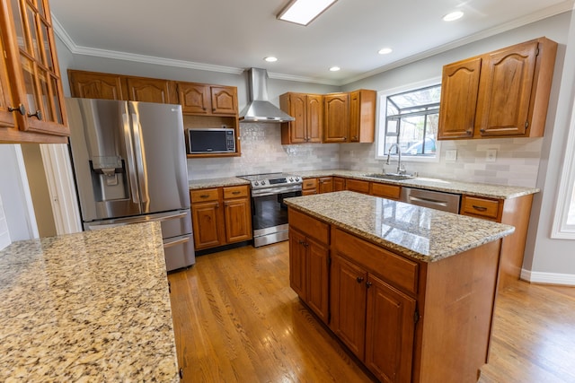 kitchen featuring light wood-style floors, light stone countertops, wall chimney range hood, appliances with stainless steel finishes, and a sink