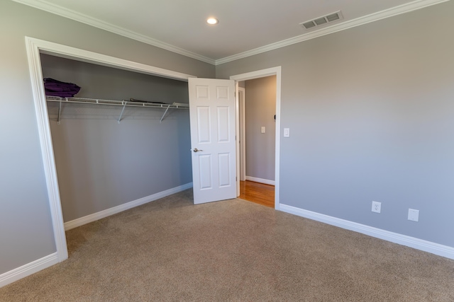 unfurnished bedroom featuring crown molding, a closet, visible vents, carpet floors, and baseboards