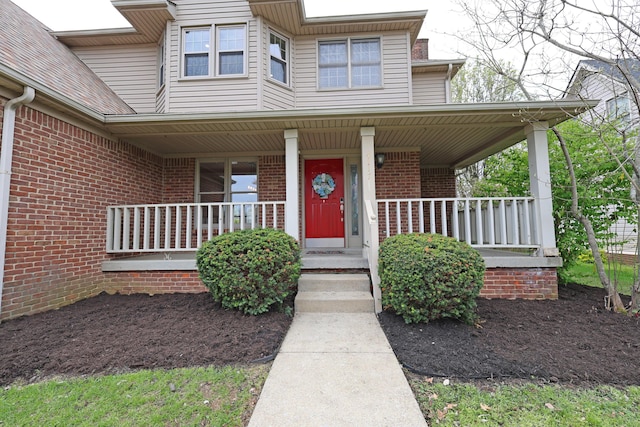 property entrance featuring brick siding and a porch