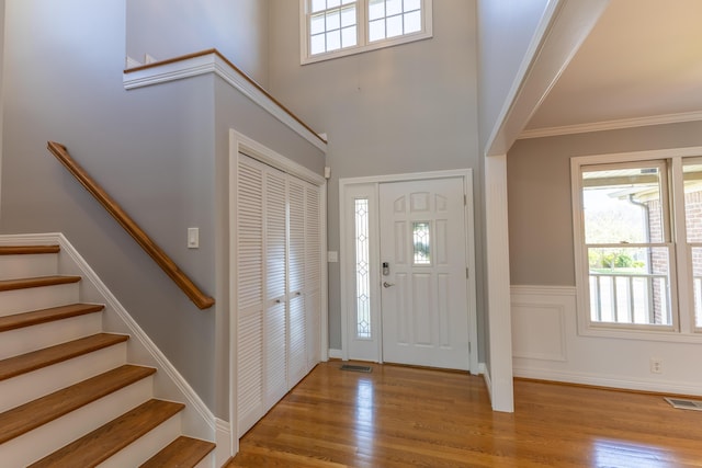 entrance foyer with plenty of natural light, stairs, visible vents, and wood finished floors