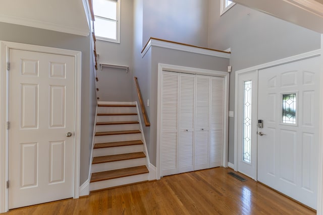 foyer with stairs, light wood-style flooring, baseboards, and visible vents
