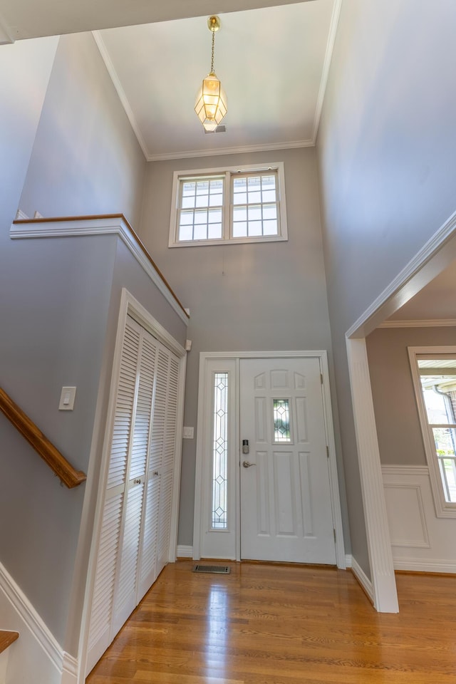 foyer entrance featuring crown molding, wood finished floors, and a wealth of natural light