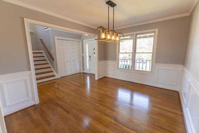 spare room with ornamental molding, a chandelier, stairway, visible vents, and wood finished floors