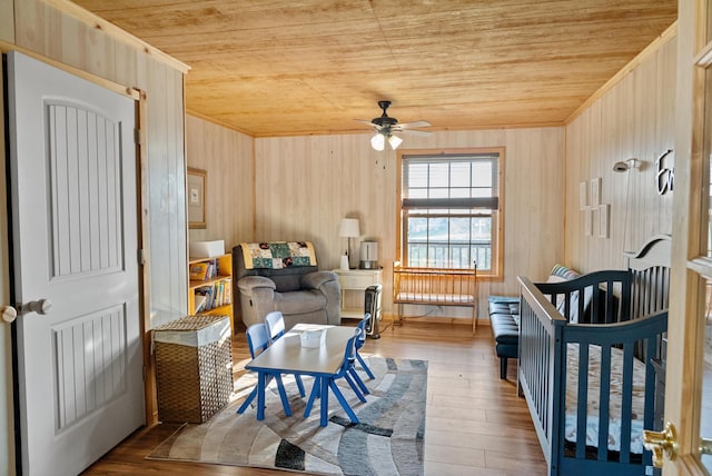 bedroom with wooden walls, wood ceiling, ornamental molding, and wood finished floors