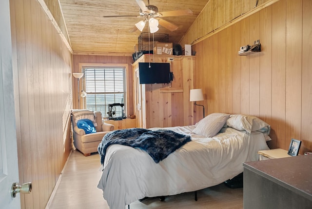 bedroom with light wood-style floors, wooden ceiling, wood walls, and lofted ceiling