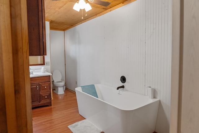 full bathroom with ceiling fan, a freestanding tub, vanity, toilet, and wood finished floors