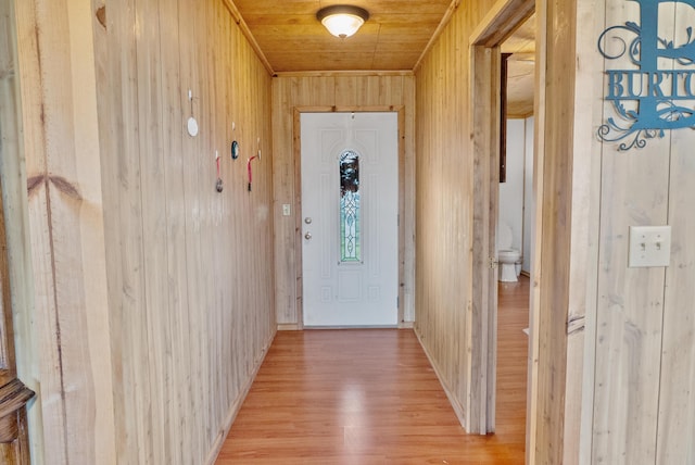 doorway to outside with wooden walls, light wood-style flooring, and wooden ceiling