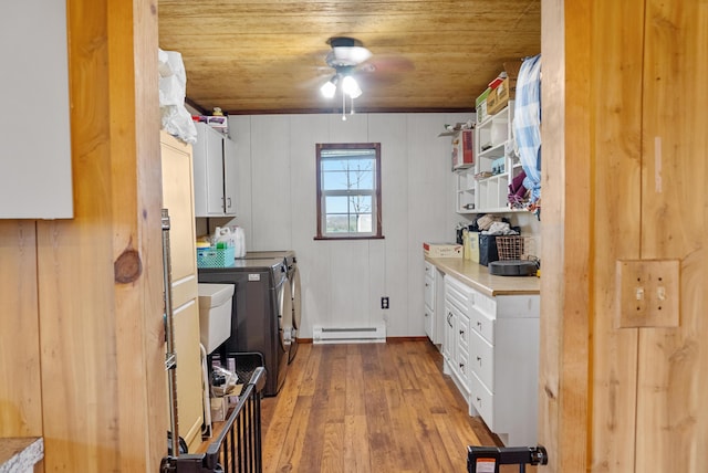 laundry room featuring a baseboard radiator, ceiling fan, independent washer and dryer, wood finished floors, and cabinet space