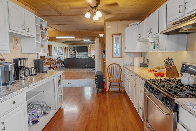 kitchen with white cabinets, under cabinet range hood, light wood finished floors, and stainless steel gas range oven
