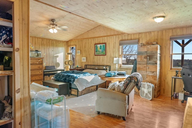 living area featuring wood finished floors, wooden walls, a ceiling fan, and lofted ceiling