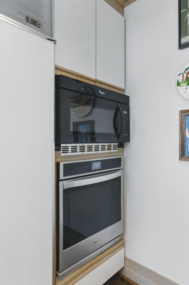 216 Ridgeway Rd, Lexington, KY 40502 - kitchen with refrigerator, baseboards, black microwave, white cabinets, and stainless steel oven