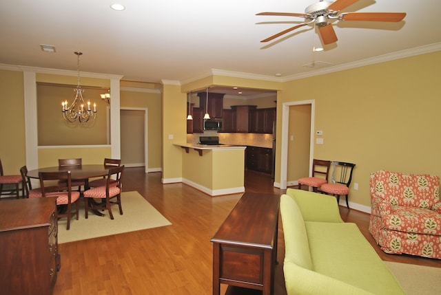 living area with visible vents, baseboards, ornamental molding, wood finished floors, and ceiling fan with notable chandelier