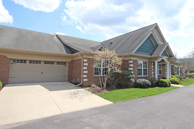 view of front facade with concrete driveway, brick siding, an attached garage, and a shingled roof
