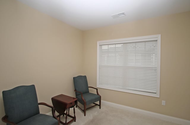 sitting room with light carpet, visible vents, and baseboards
