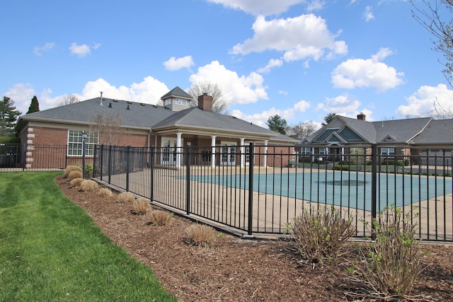 community pool featuring a patio area, fence, and a lawn