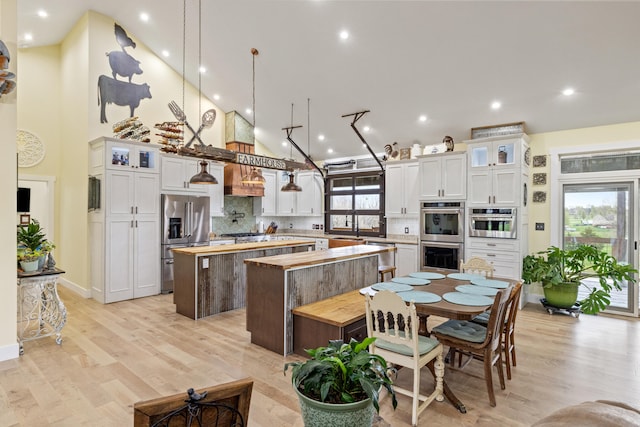 kitchen featuring a center island, stainless steel appliances, butcher block countertops, decorative backsplash, and high vaulted ceiling